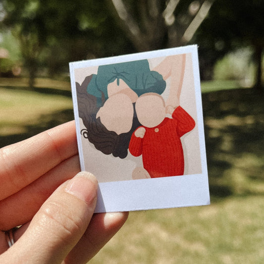Hand holding a personalized illustrated Polaroid-style magnet featuring a mother and baby, custom drawn from a photo – unique fridge keepsake
