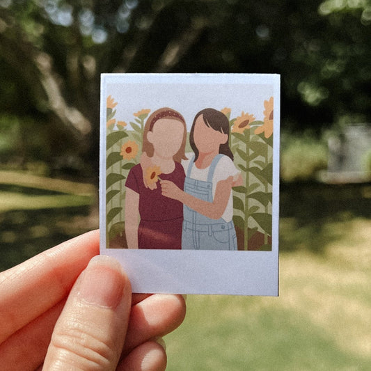 Hand holding a personalized illustrated Polaroid-style magnet of two girls standing in a sunflower field – custom photo art keepsake for sisters or best friends